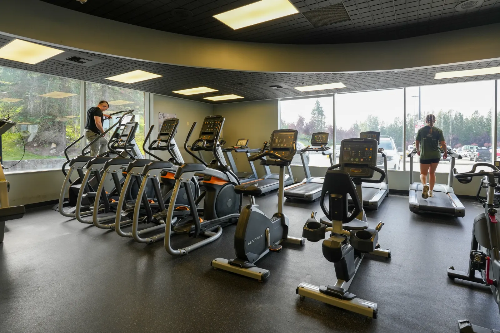 Row of ellipticals, exercise bikes, and treadmills by the windows at BR Fitness in East Anchorage