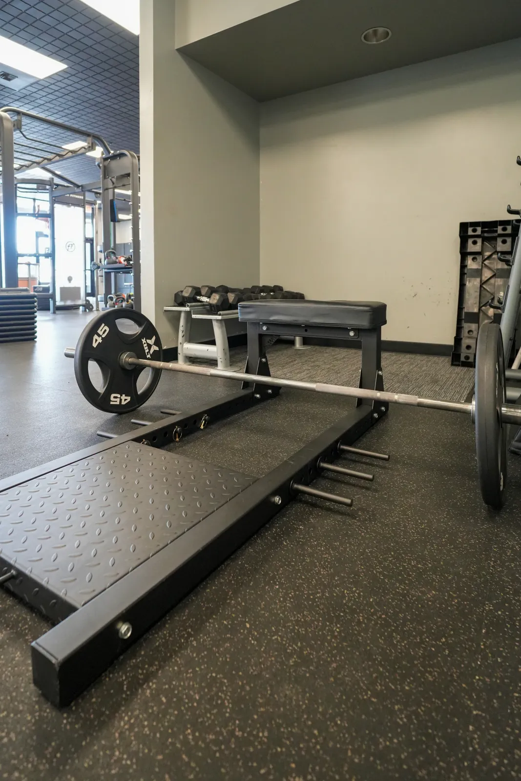 Deadlift platform with a loaded barbell, flat bench, and dumbbells at BR Fitness in East Anchorage